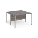 Dams Maestro 25 600mm deep back-to-back straight desks with bench legs in grey oak, showing a sleek modern office setup.