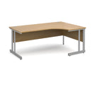 Dams Momento ergonomic desk with oak finish and cantilever leg, shown from the left side. Modern office workspace furniture.