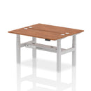 Walnut-colored Air 2-person back-to-back slimline height-adjustable bench desk by Dynamic, showing the modern, compact workspace design.