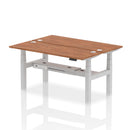 Walnut 2-person back-to-back slimline height adjustable bench desk by Dynamic, showing the modern, space-saving design and wooden finish.
