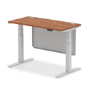 Dynamic Air 600mm deep height-adjustable desk with walnut finish, cable ports, and steel modesty panel, shown in the image.