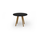 Black Unity circular dining table with solid oak legs by Dams, showcasing a sleek modern design and smooth tabletop surface.