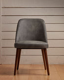 ZAP Aztec side chair with faux leather upholstery, featuring a modern design and wooden legs, placed in a cozy indoor setting.