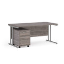 Dams Maestro 25 straight desk with grey oak finish and silver accents, featuring a 2-drawer under-desk pedestal for storage.